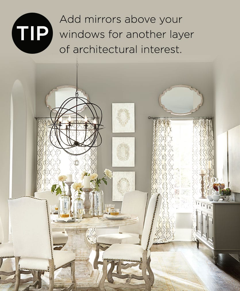 This neutral dining room has mirrors hanging over the windows