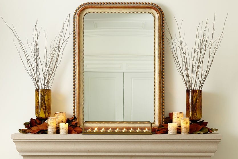 Fall Mantel decorated with branches, magnolia leaves, and candles