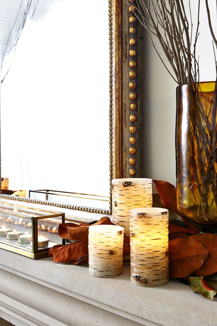 Fall Mantel decorated with branches, magnolia leaves, and candles