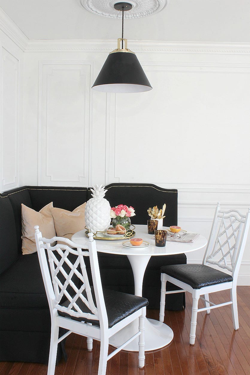 A chic black banquette nestled into the corner of this gold & marble kitchen I banquette by Ballard Designs