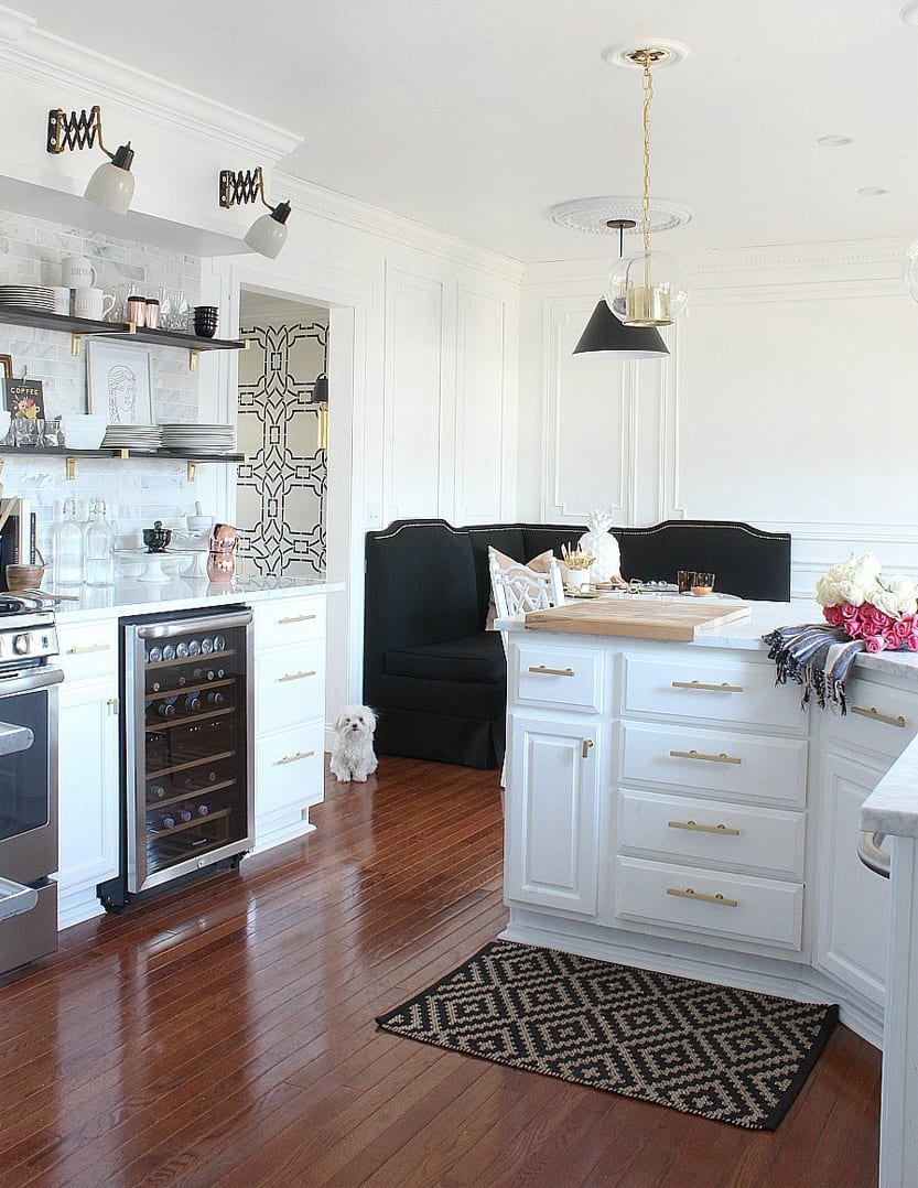 A chic black banquette nestled into the corner of this gold & marble kitchen I banquette by Ballard Designs