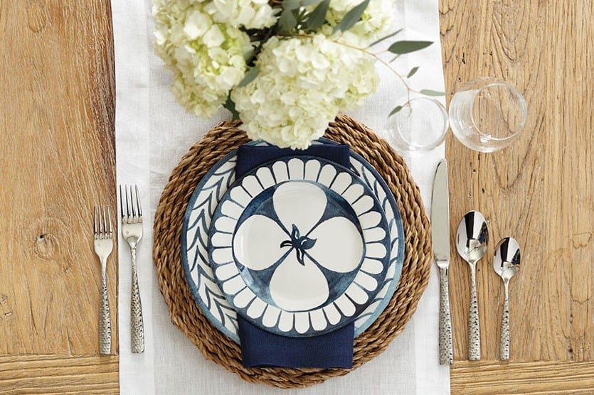 Bunny Williams' Watercolor Iris melamine dinnerware collection is a classic navy and white -- perfect for entertaining outdoors with big hydrangea blooms and rattan charger.