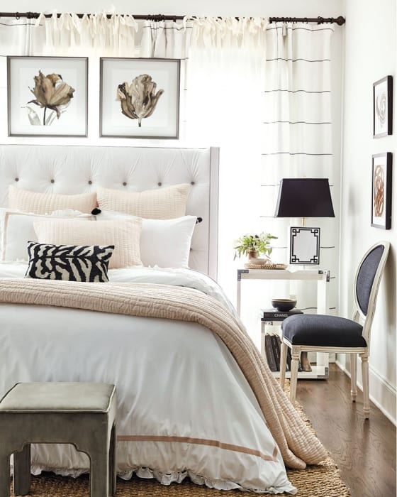 Bedroom with a white headboard and bedding and black and blush pink accents