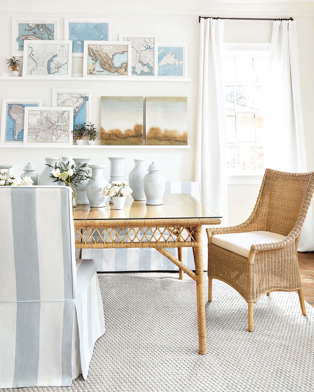 Blue and white dining room with rattan wicker dining table and chairs and blue and white striped fabric designed by Suzanne Kasler for Ballard Designs