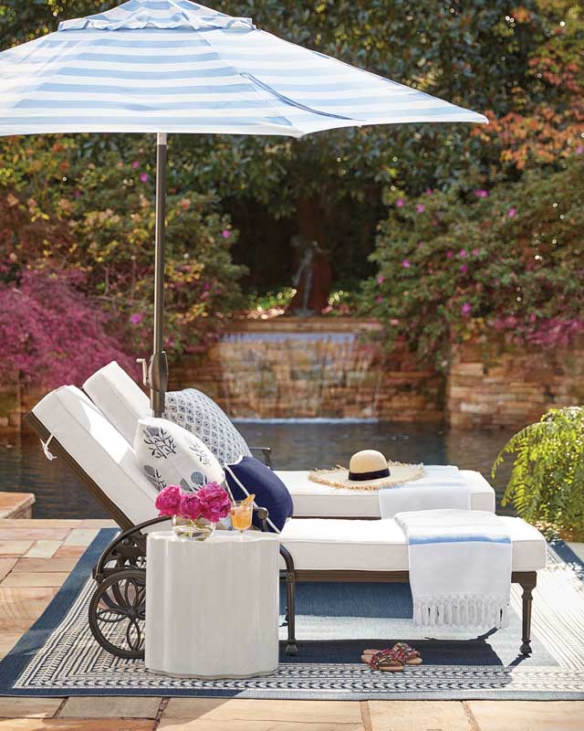 Pair of chaise lounges with blue and white striped umbrella