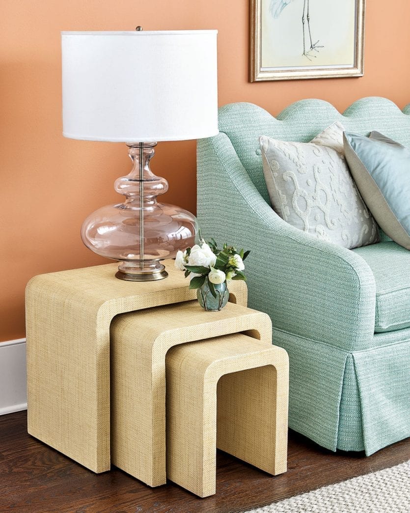 Three raffia wrapped nesting tables next to sofa designed by Bunny Williams for Ballard designs