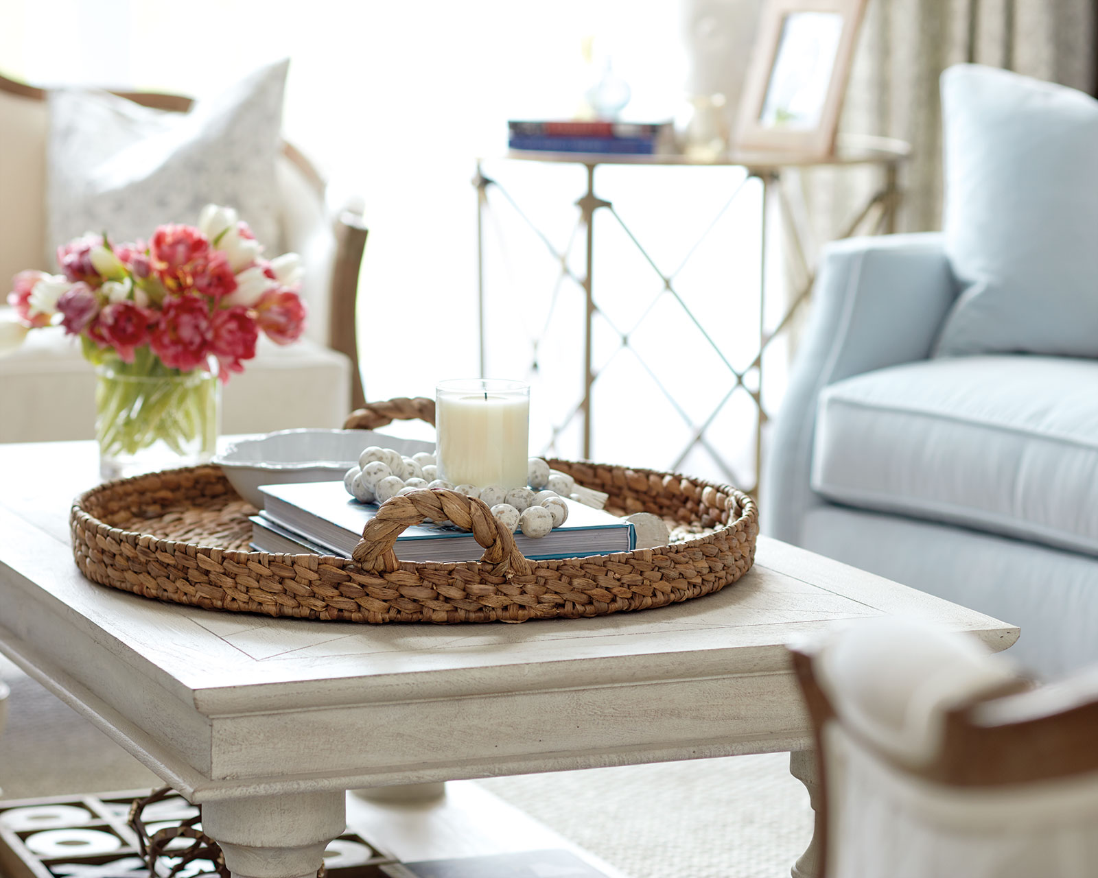 Coffee table with fresh flowers, tray, and candle in living room of blogger Caitlin Covington