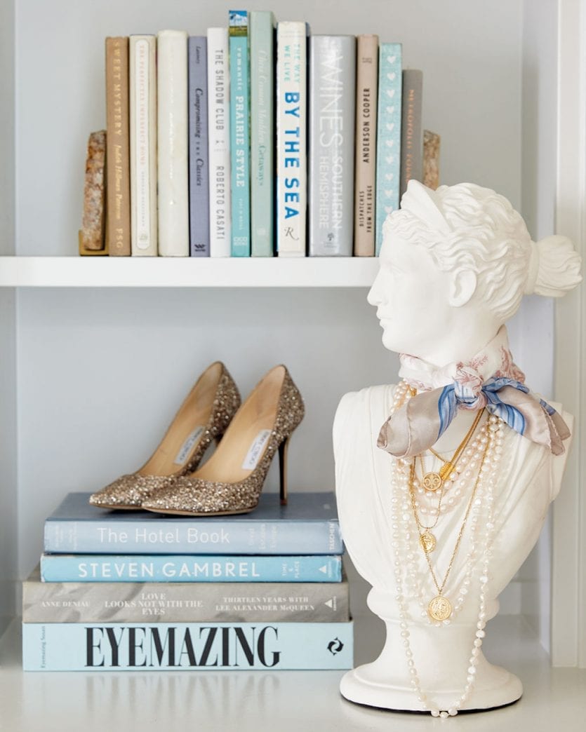 Tabletop bust with jewelry and scarf and bookshelves styled with shoes