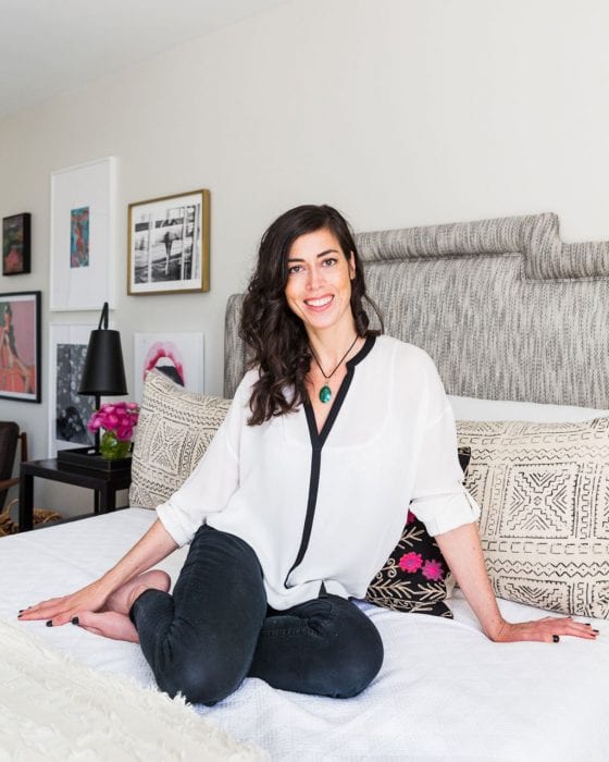 Interior designer Naomi Stein sits on a white bed