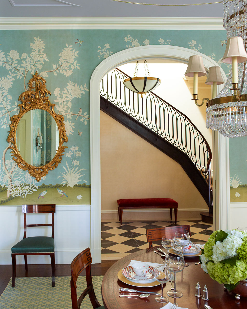 Dining room with chinoiserie wallpaper, gilded mirror, and arched doorway