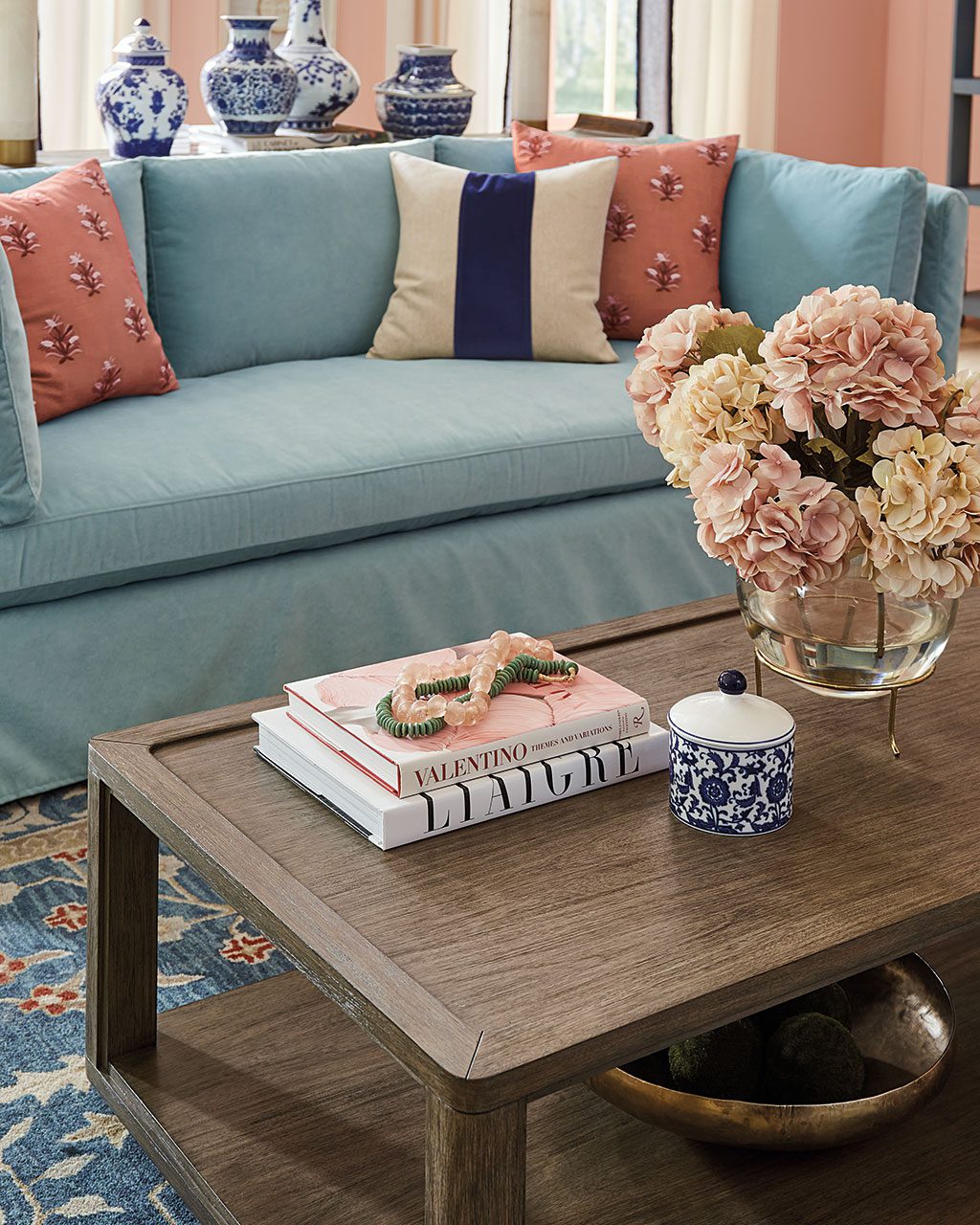 Coffee table in a blue and white living room with accents of pink; by Ballard Designs